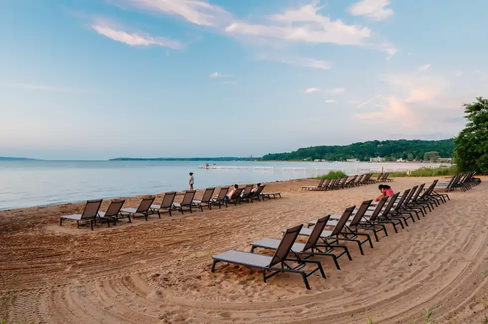 Rows of lounge chairs set out on the raked sand at the water's edge