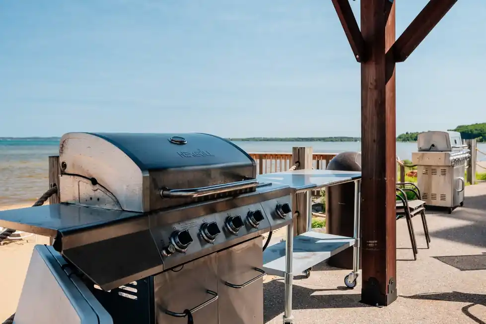 An outdoor grill in the foreground with the bay stretching away behind it