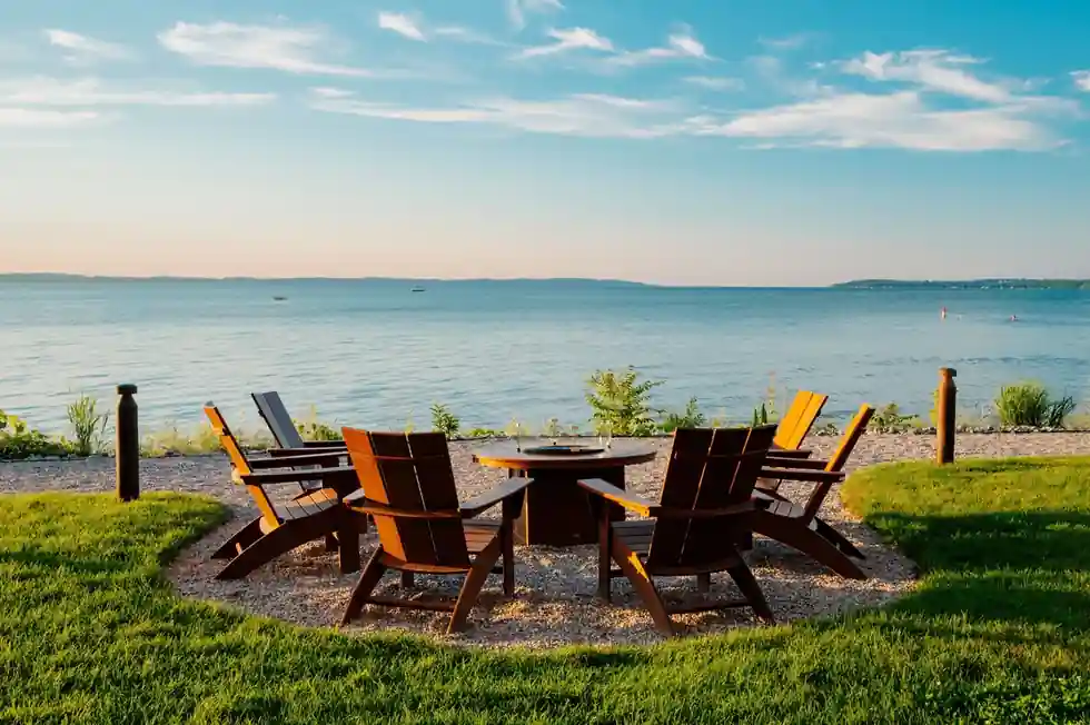 Adirondack chairs around a fire pit on the lawn above the bay