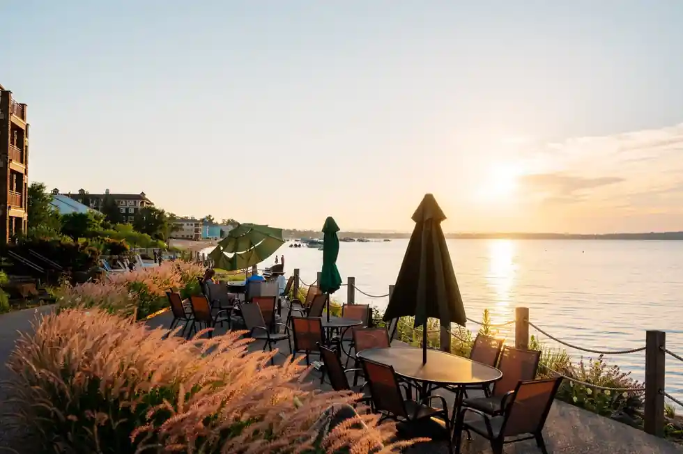 Terrace tables under umbrellas at sunset beside the bay