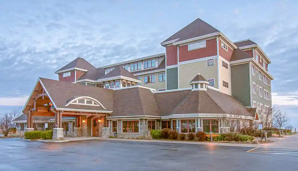 Main lodge entrance at dusk with its timber porte cochere lit against the evening sky
