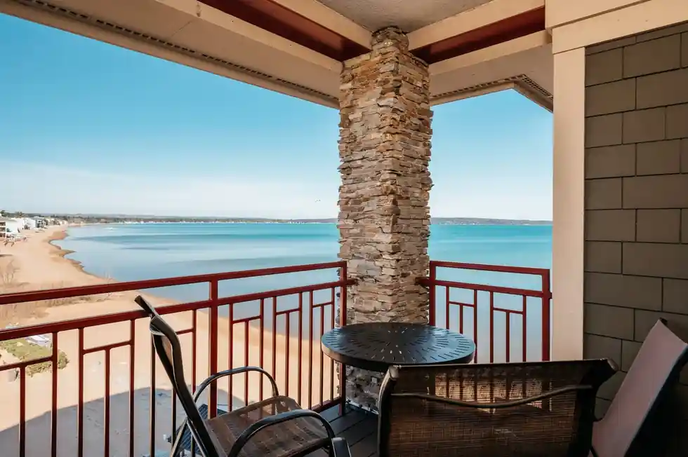 Balcony table beside a fieldstone column, the beach and bay below