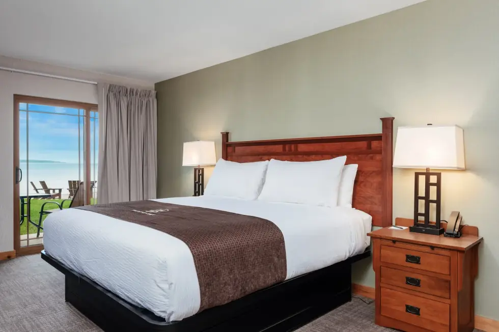 King bed in a walkout room, the patio door open to the lawn and the bay