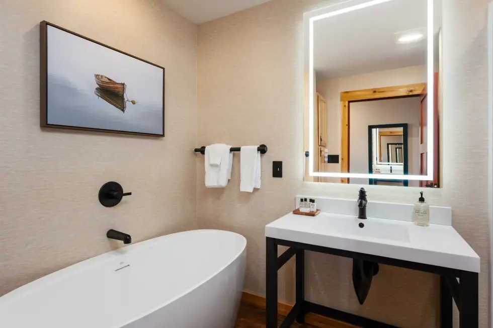 Bathroom with a lit mirror and a tub
