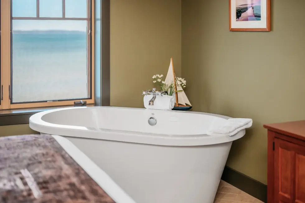 Freestanding soaker tub beside a window full of open bay